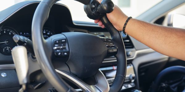 A disabled man in the driver seat of a car modified to drive with hands only.